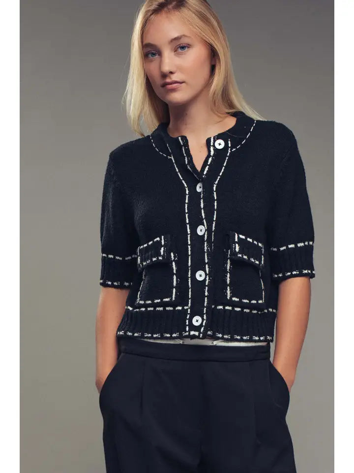 Woman wearing a black knitted cardigan with white trim