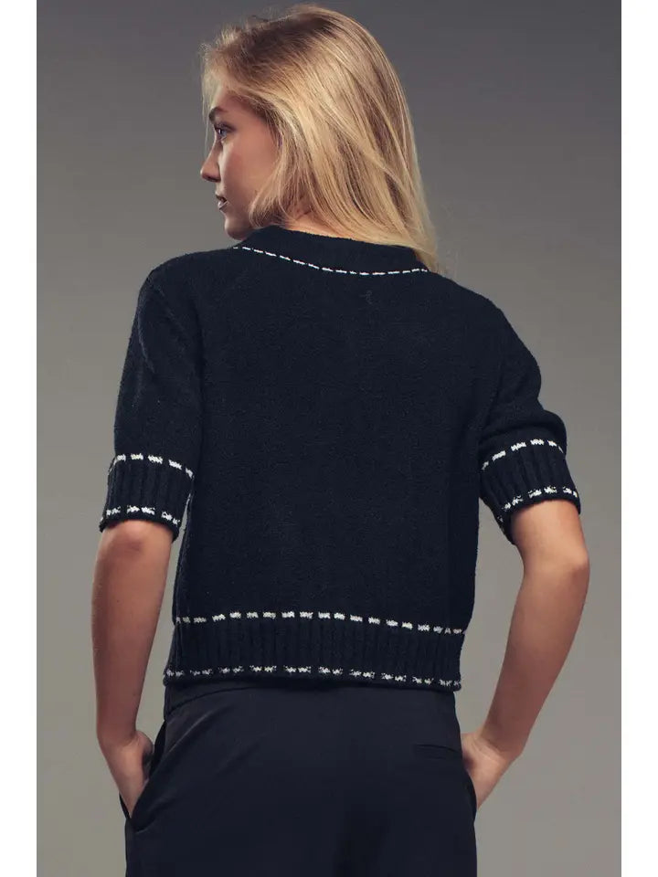 Woman wearing a black sweater with white trim