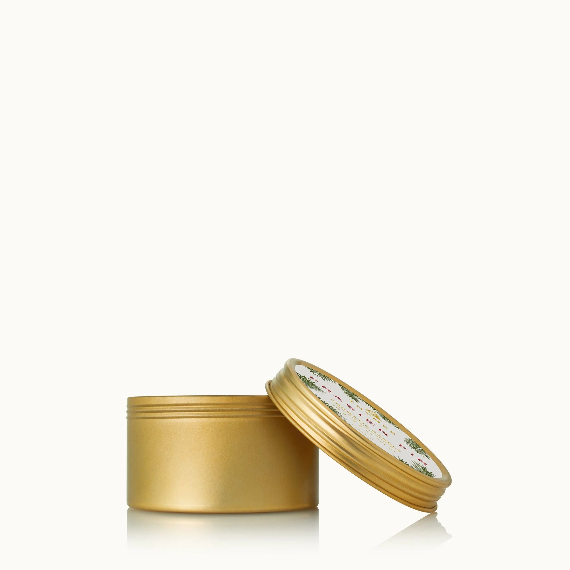 A gold travel tin candle with a label featuring Frasier Fir needles.