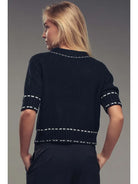 Woman wearing a black sweater with white trim 